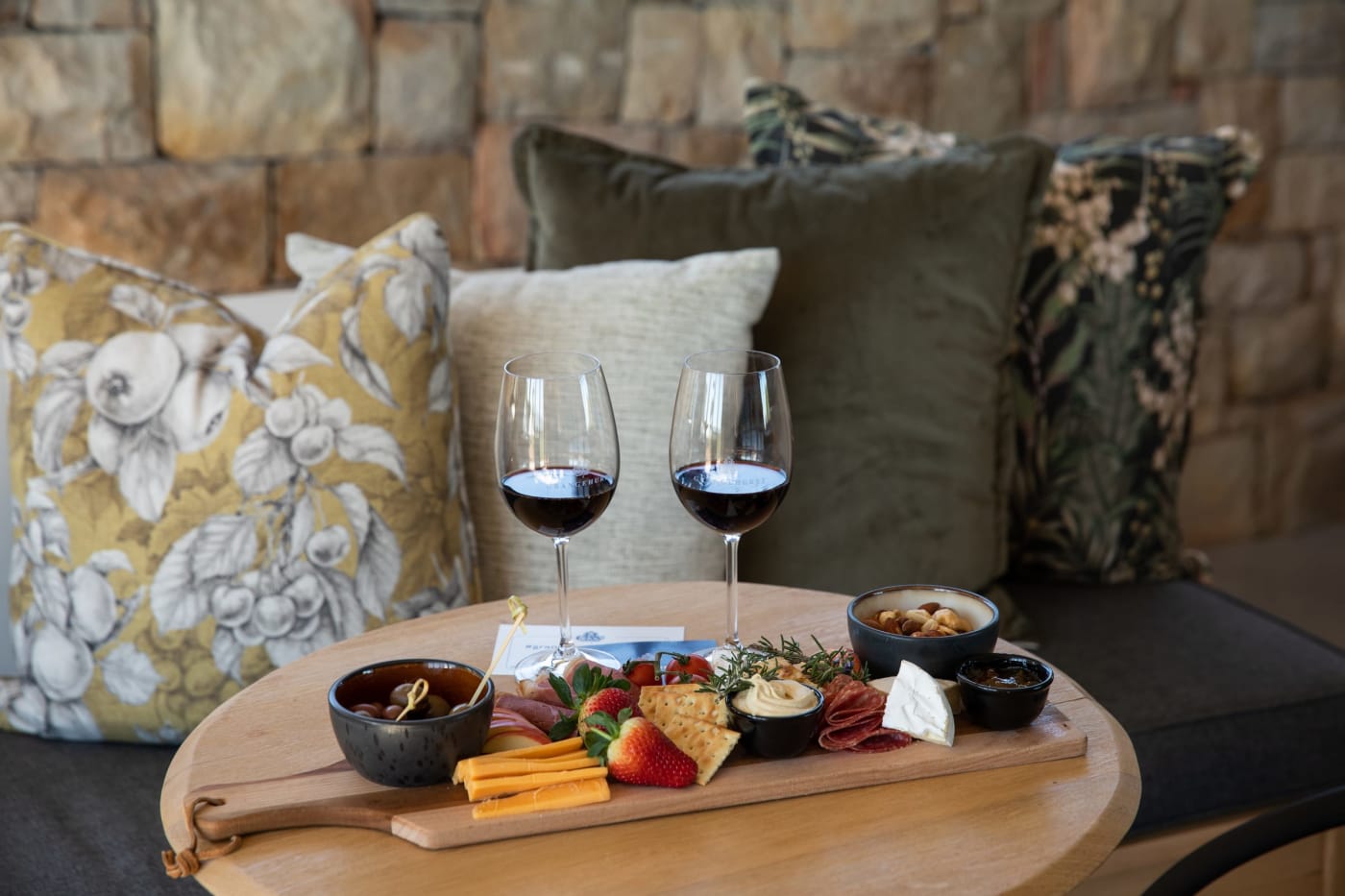 Two glasses of red wine and a snack board on a couch in the Grangehurst tasting room