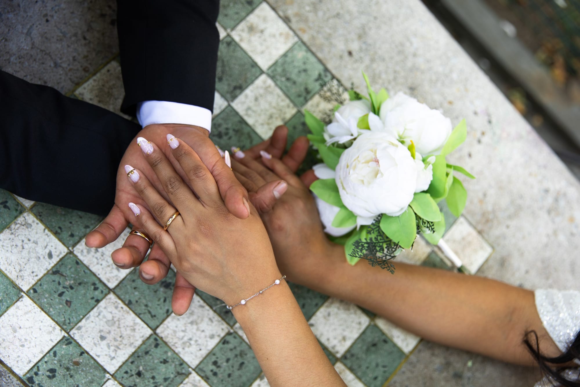 Hands and wedding rings resting on the bouquet on tiled floor after a New York elopement