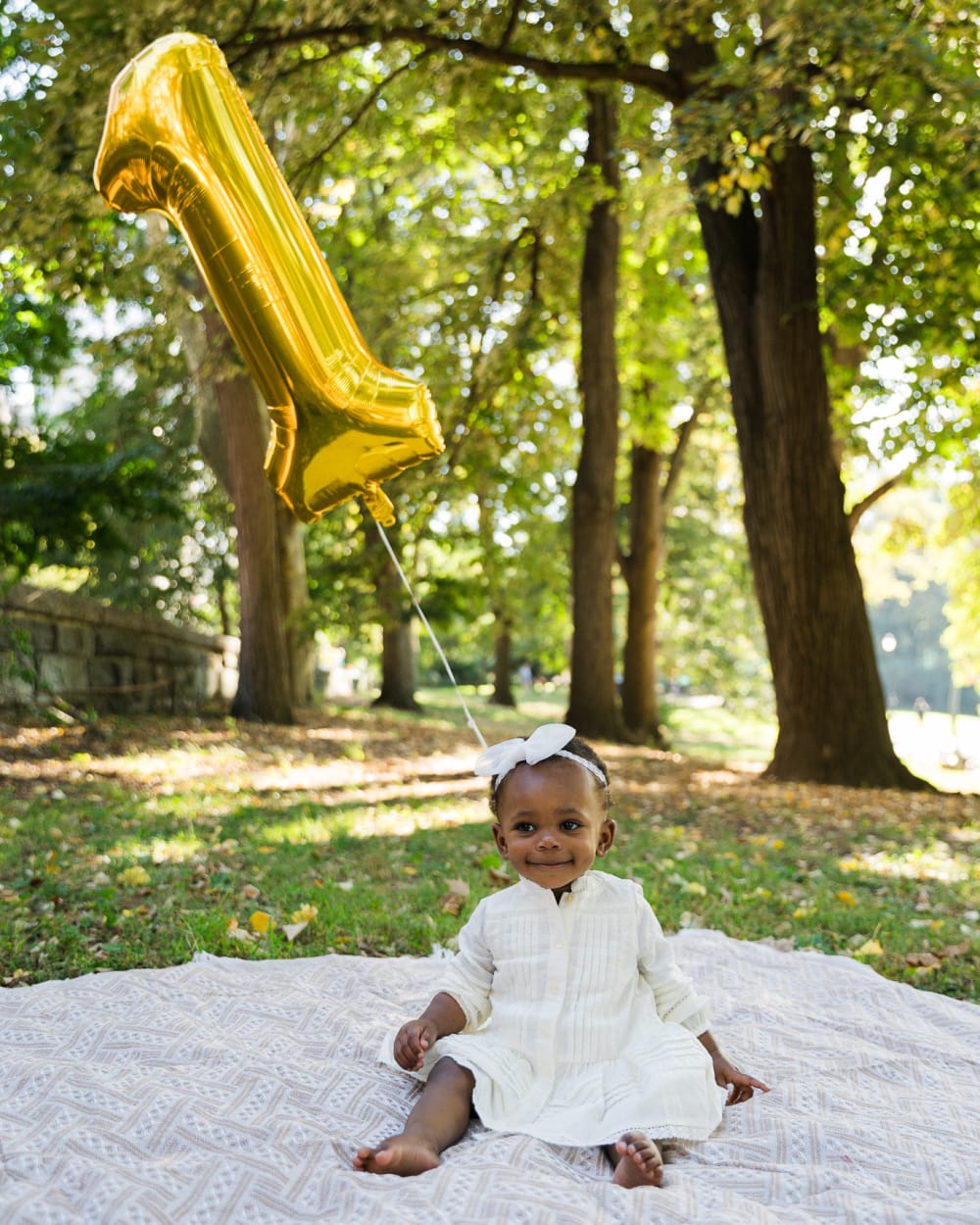 A one-year-old with a gold number one balloon in Riverside Park