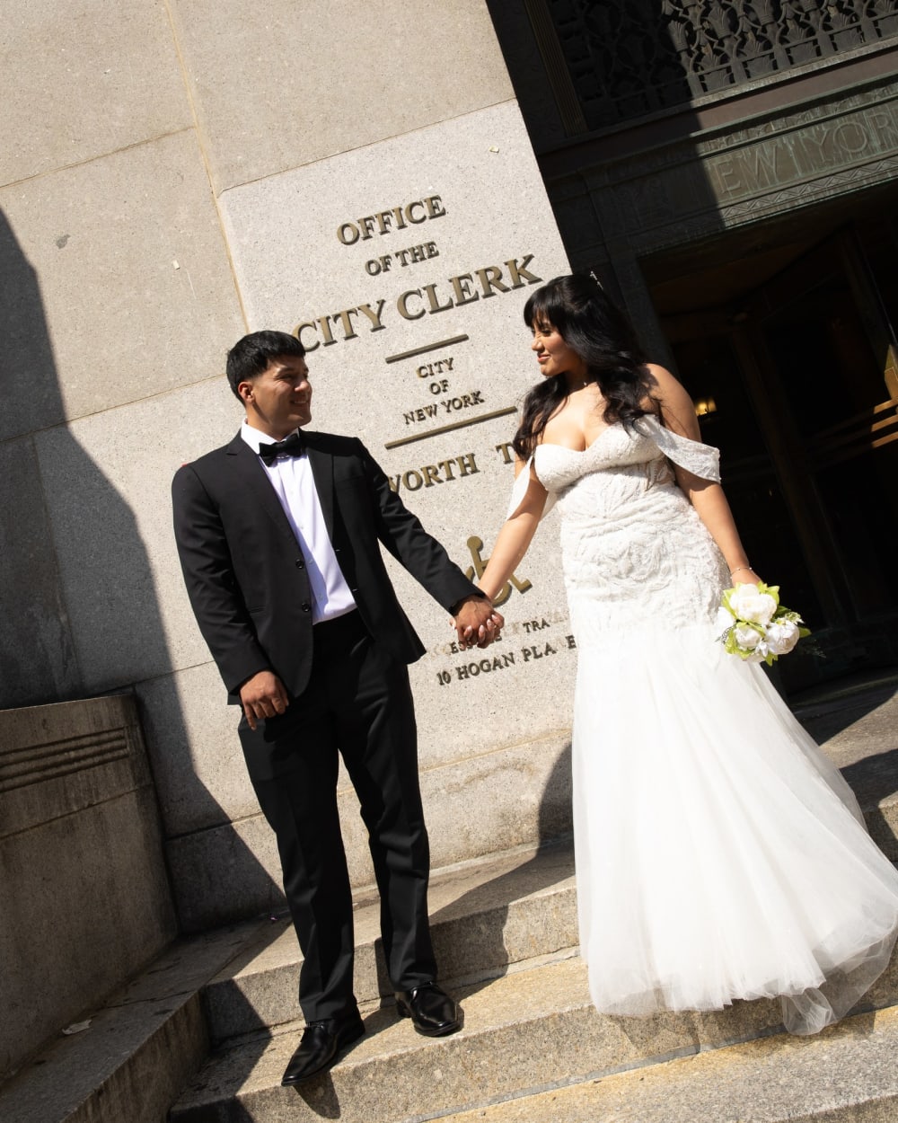 Newlyweds beside the Office of the City Clerk sign in Lower Manhattan