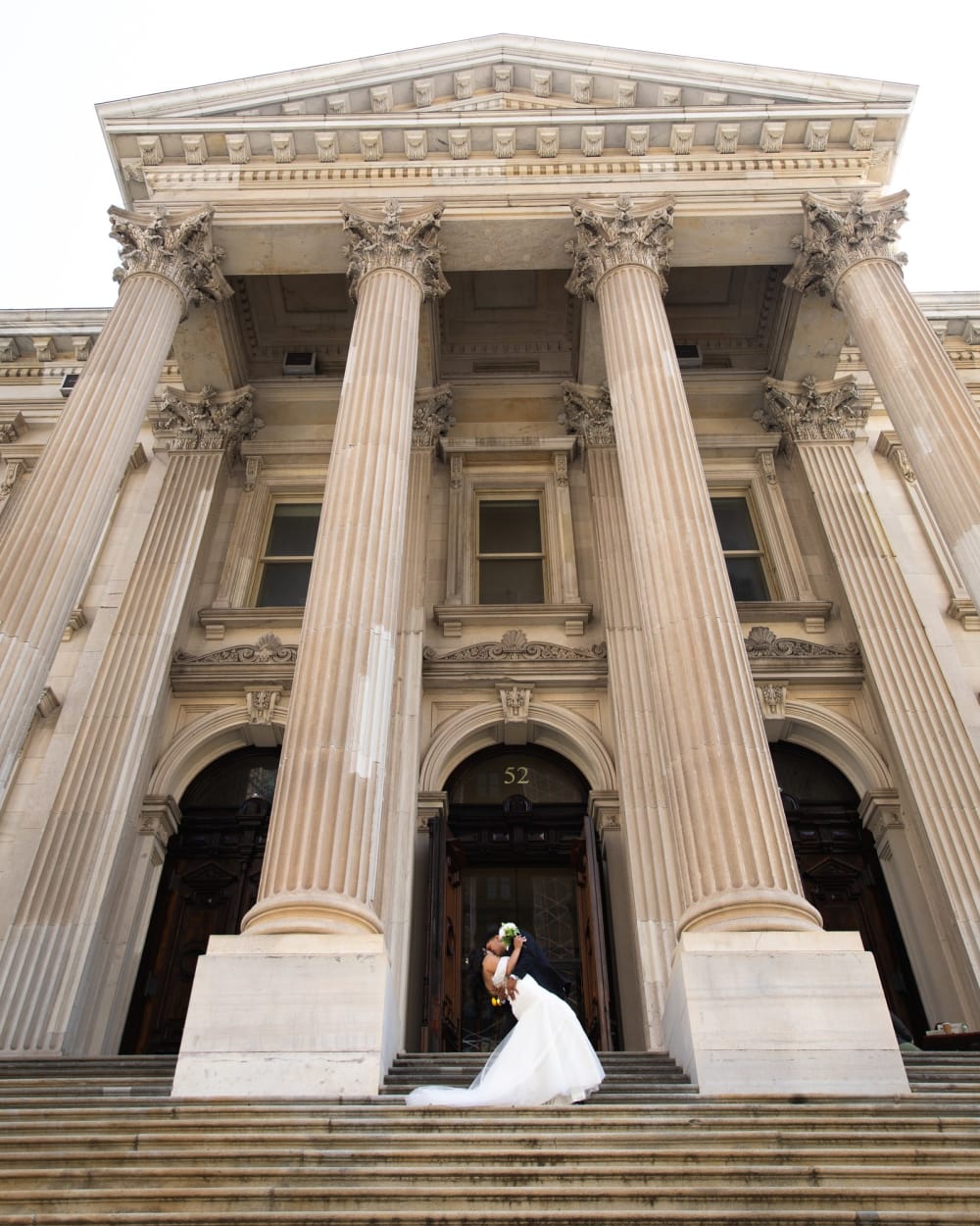 Newlyweds on the steps of a columned building near City Hall Park, New York