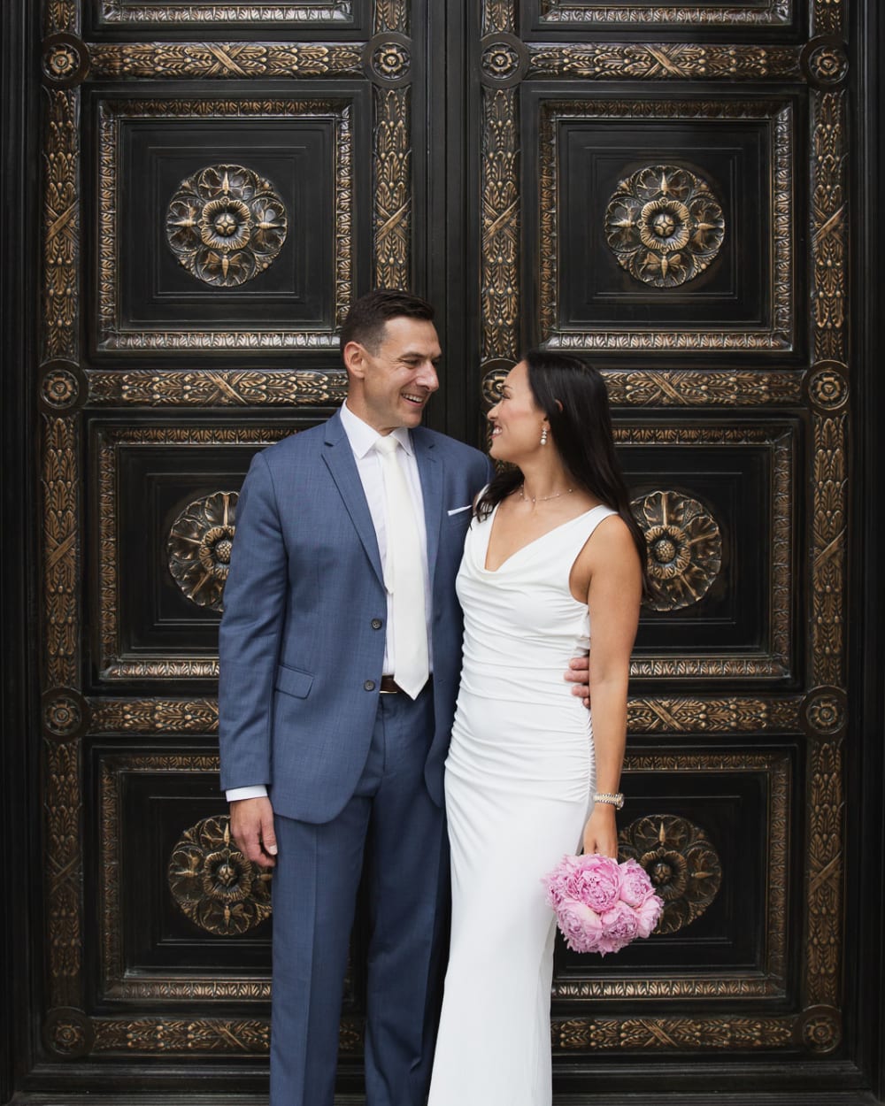 Bride and groom in front of the ornate bronze doors of a civic building near City Hall, New York
