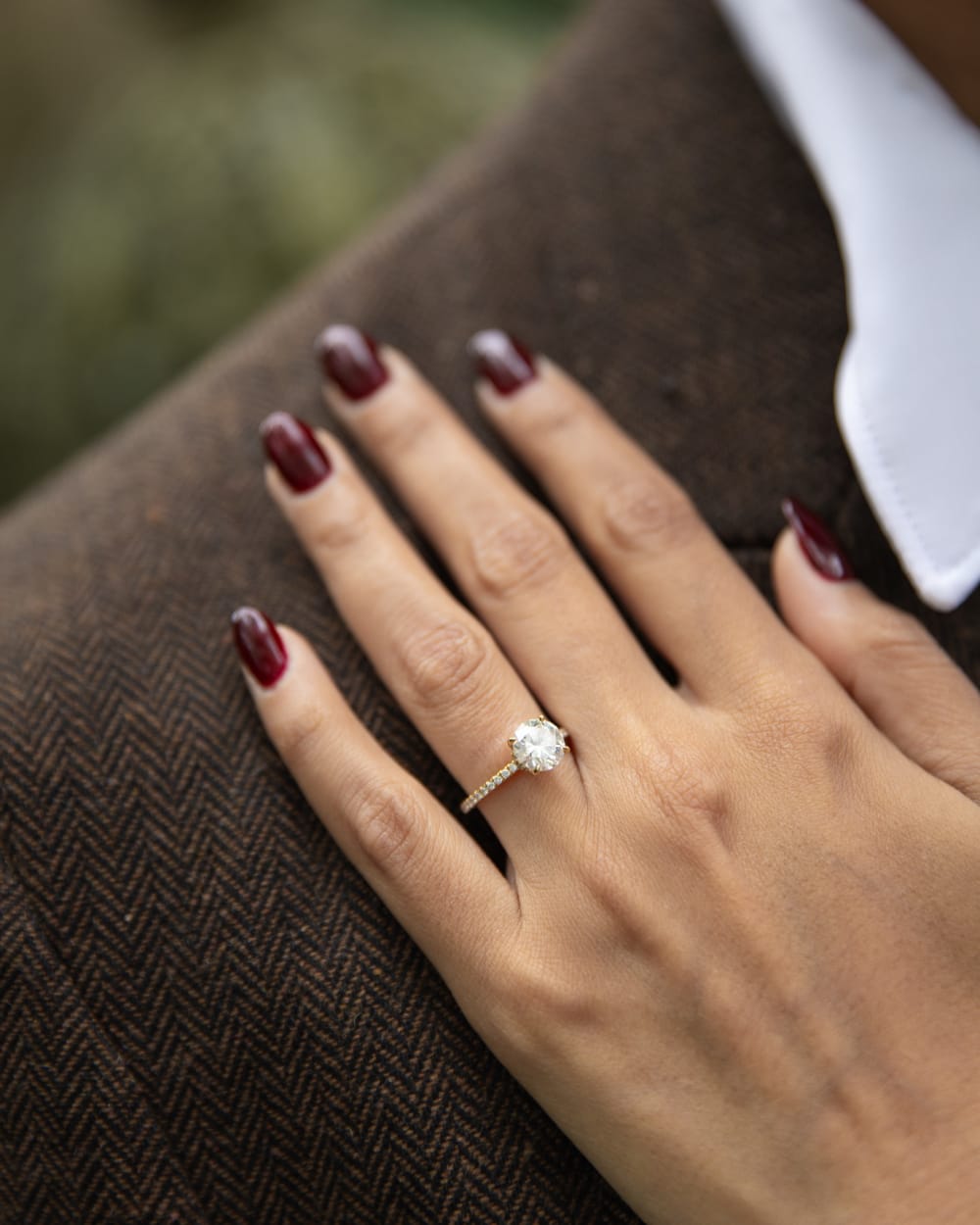 A close detail of the engagement ring, her hand resting on his lapel