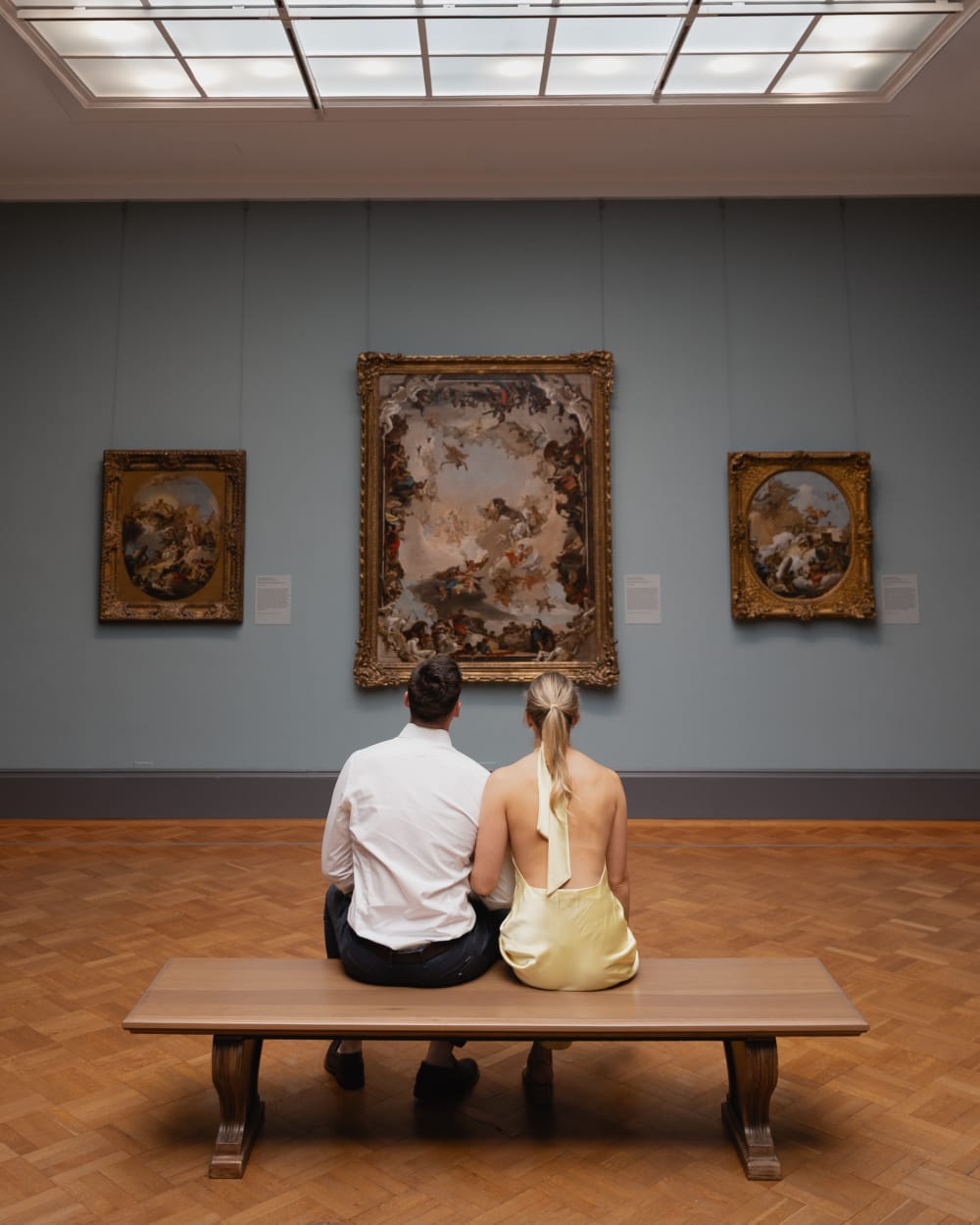 Couple sitting on a bench in front of a large painting at the Met