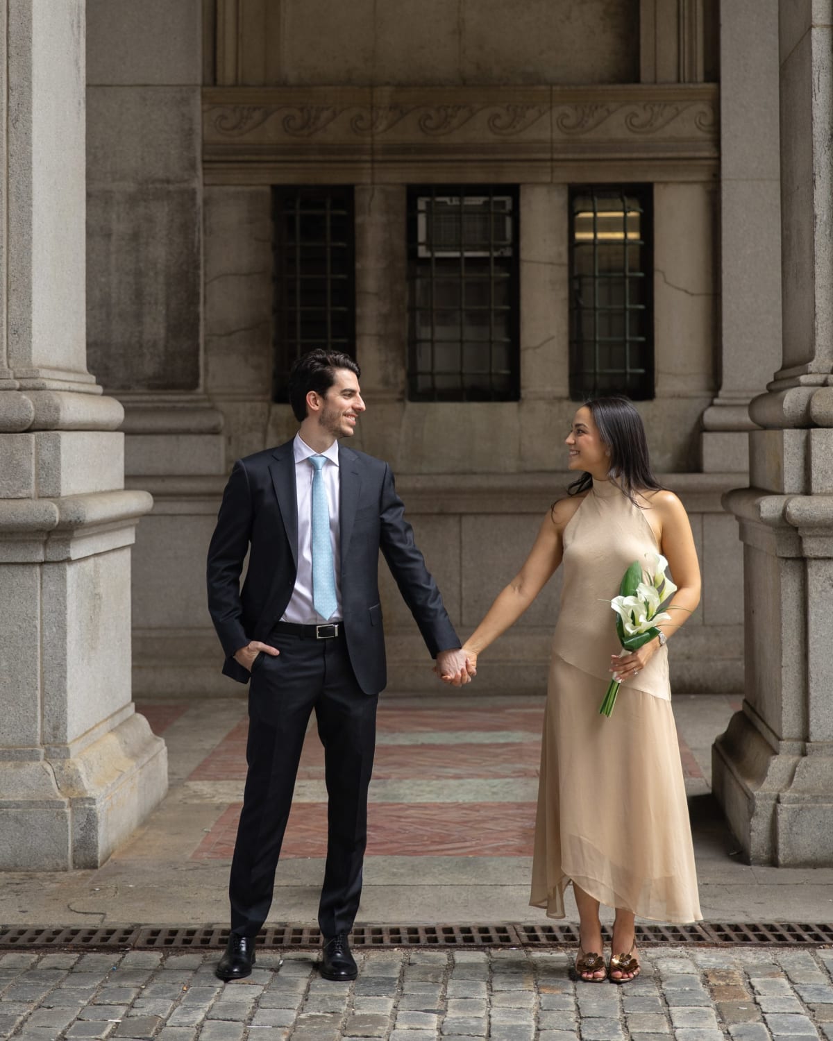 Alvaro and Maria holding hands under the colonnade at New York City Hall