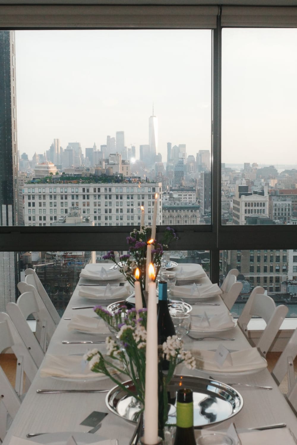 A candlelit dinner table set in front of the Manhattan skyline