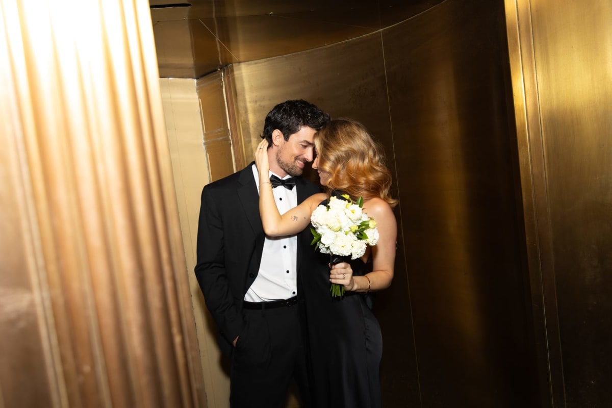 A newly married couple embracing in a gold-panelled lobby