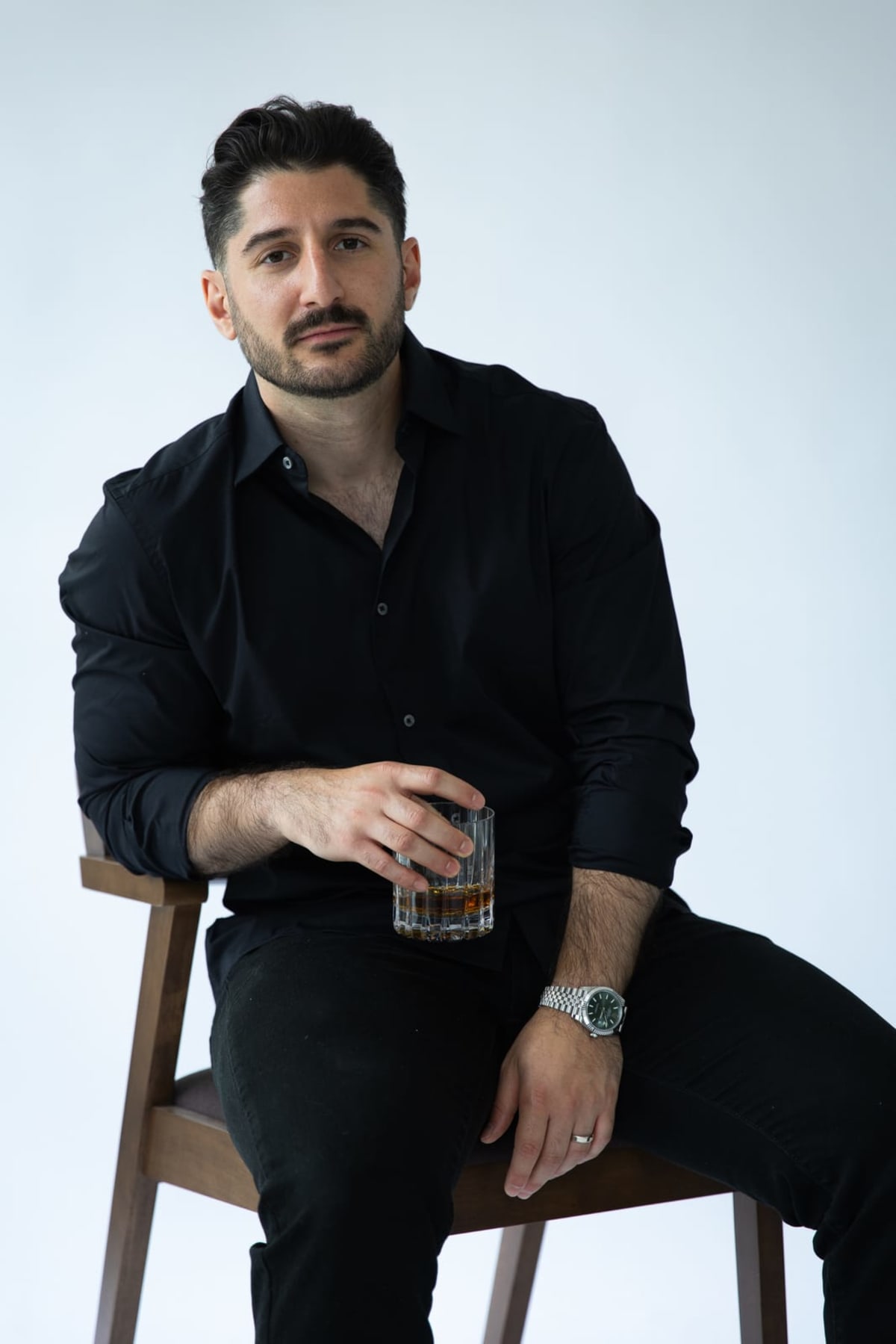 A man seated on a chair in a studio portrait
