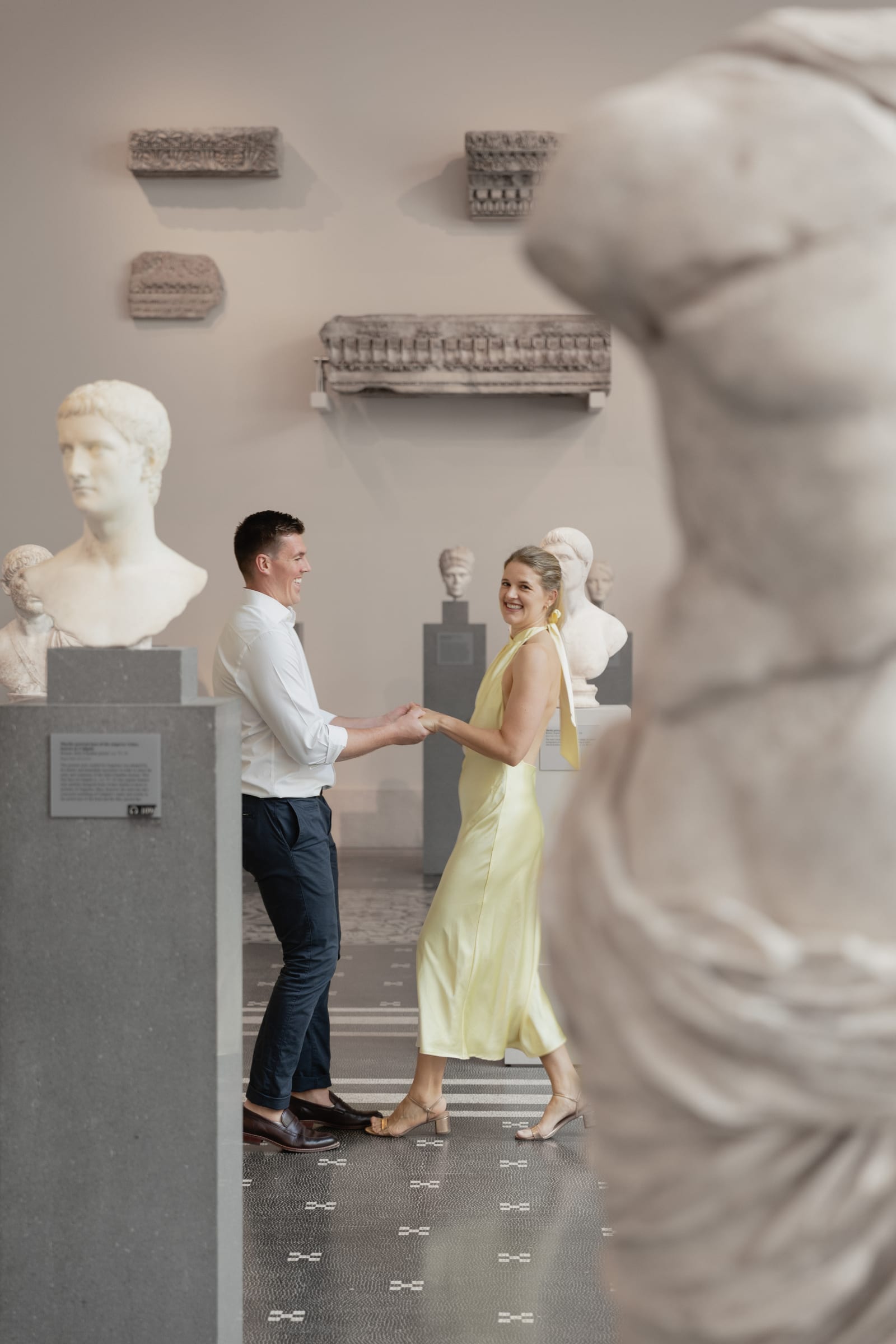 Couple holding hands among the marble sculptures at the Metropolitan Museum of Art