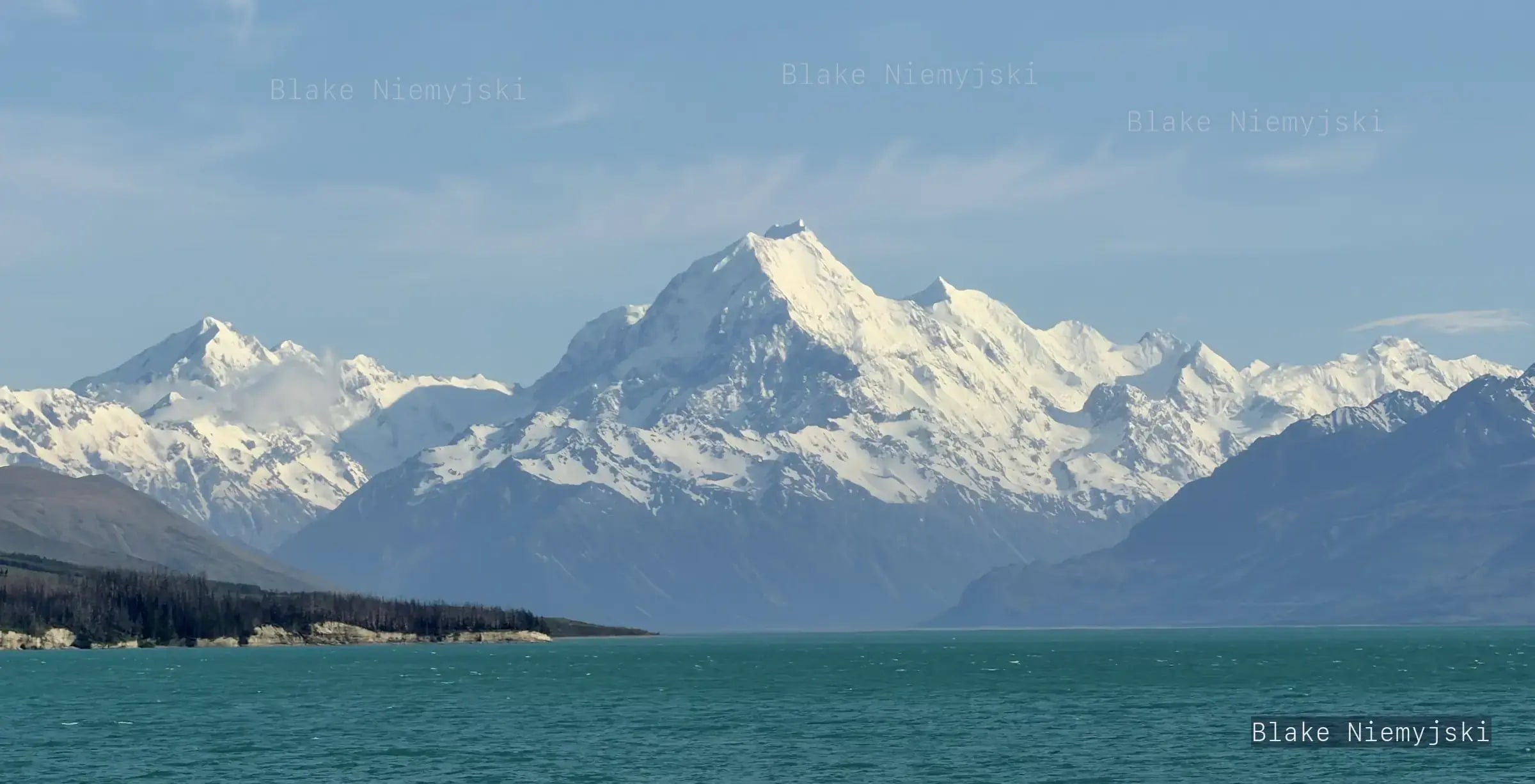 Snow-covered mountain range over a turquoise lake