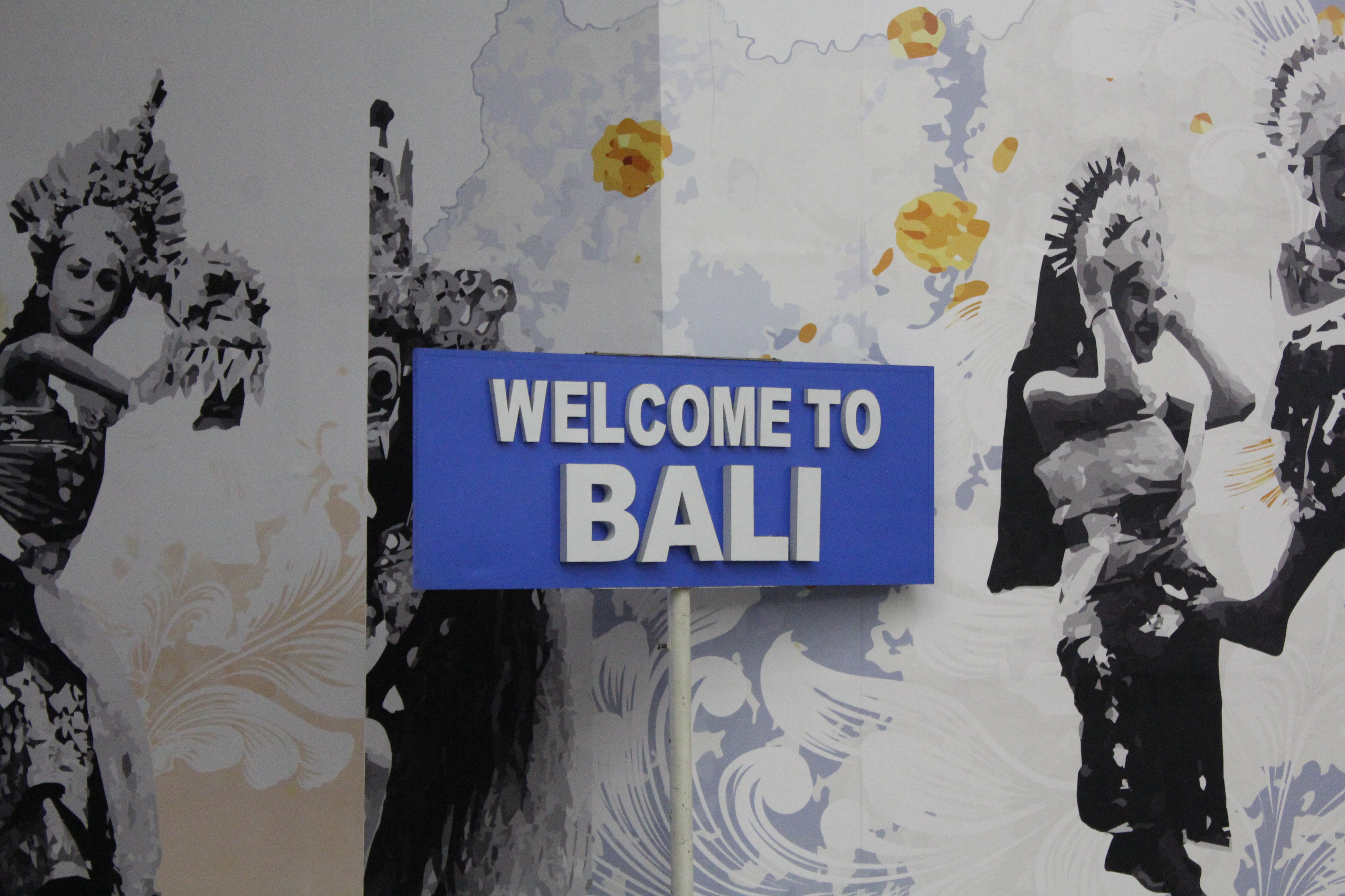 Welcome to Bali sign with traditional Balinese dancers in the background