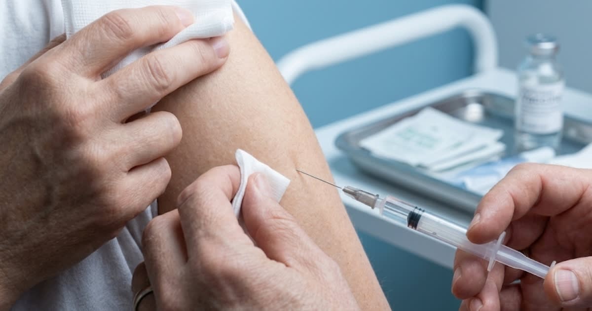 Seringue vaccinale préremplie et flacon de vaccin sur surface blanche de laboratoire