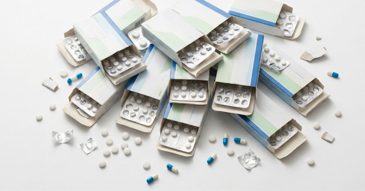 Boîtes de médicaments empilées sur un comptoir de pharmacie, ambiance sobre