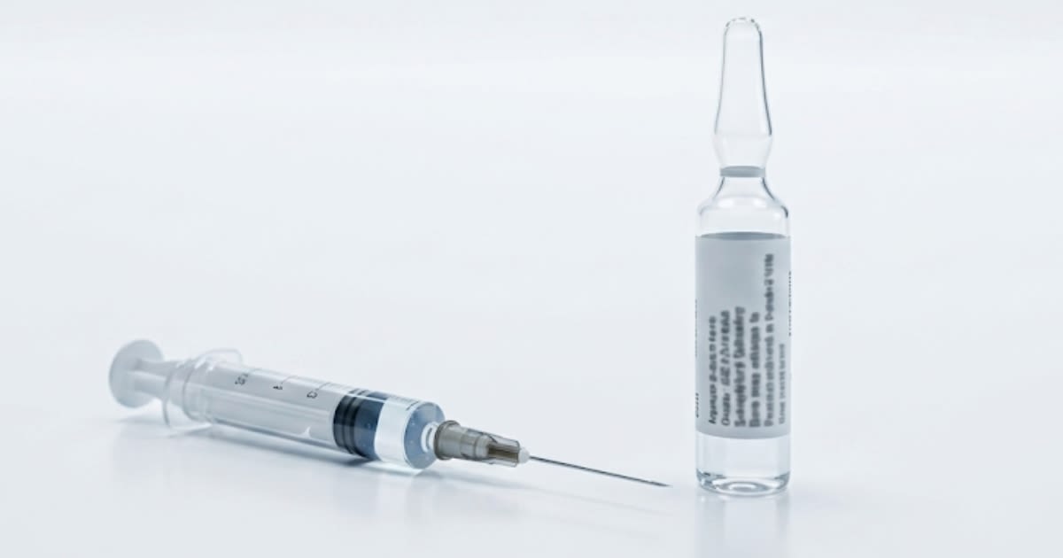 Seringue préremplie et flacon pharmaceutique sur surface blanche, ambiance officine clinique