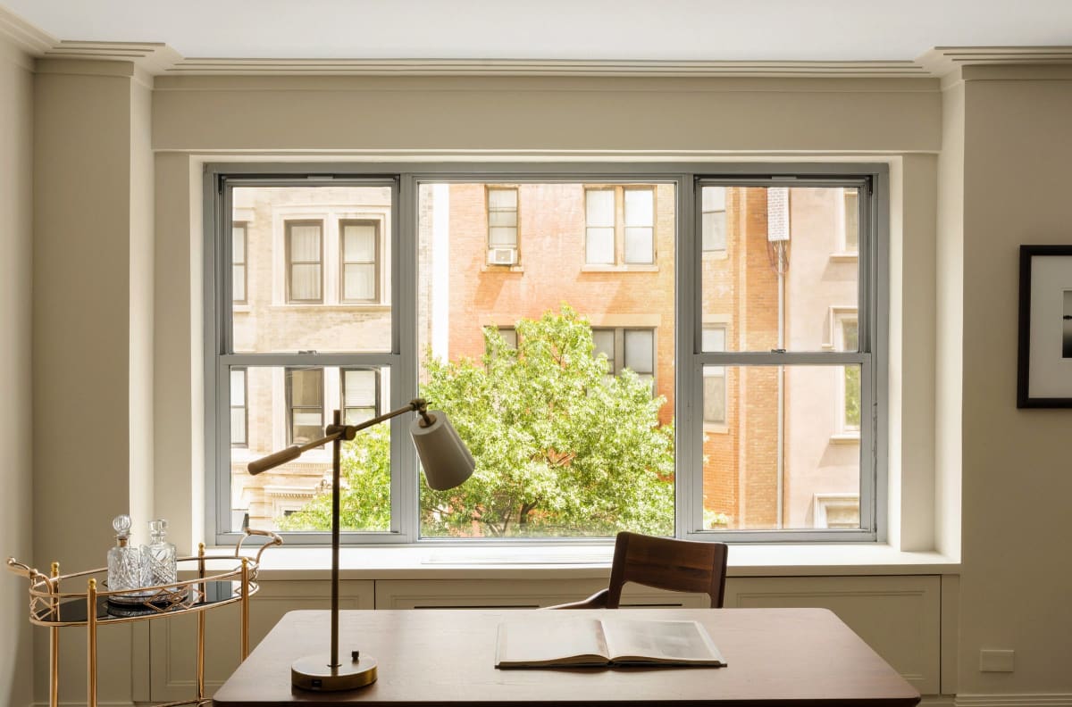 A writing desk at the window, treetops beyond