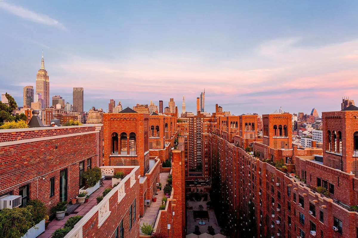 The rooftops of London Terrace at dusk, the Empire State Building lit in the distance