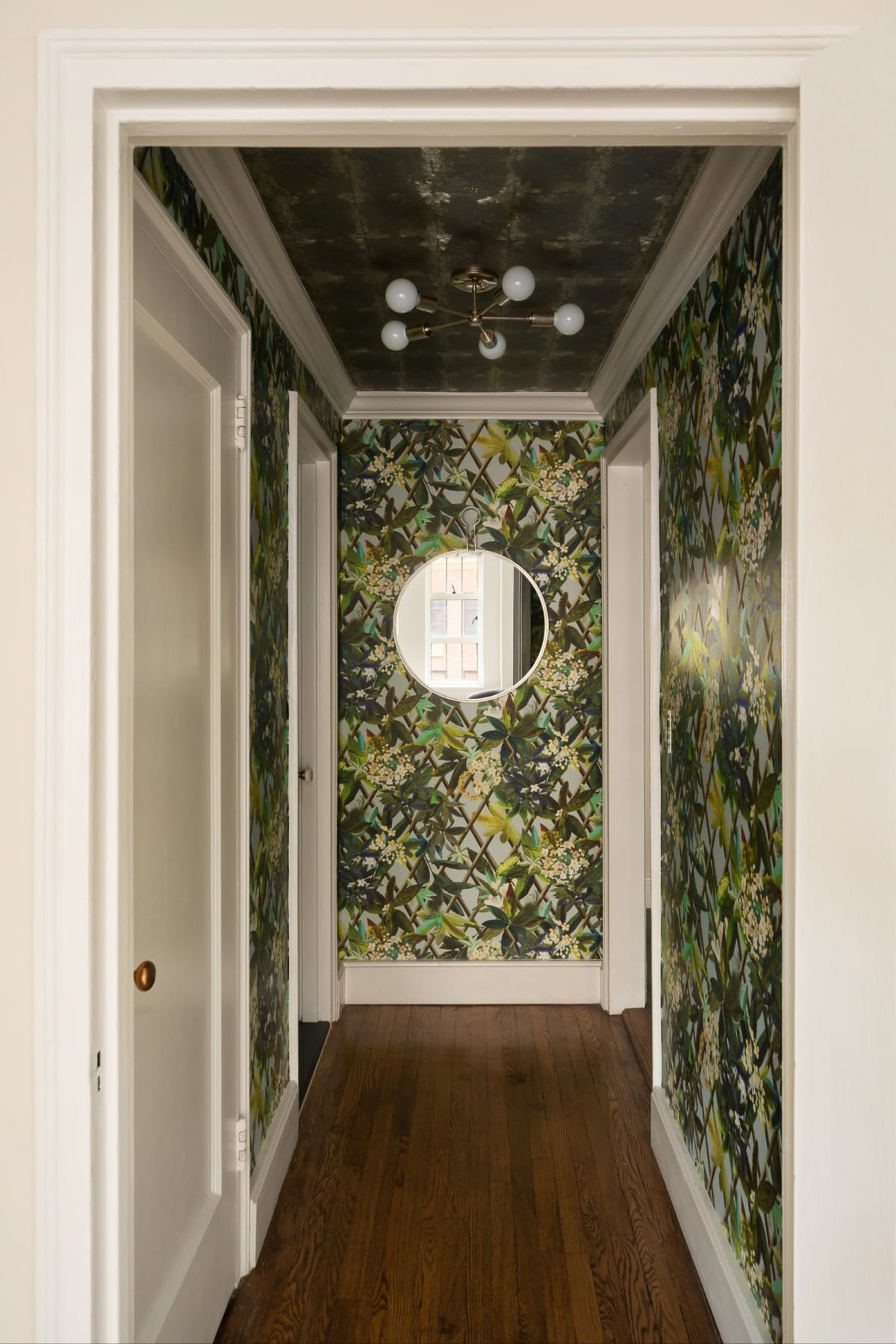 The botanical-wallpapered hallway with porthole mirror