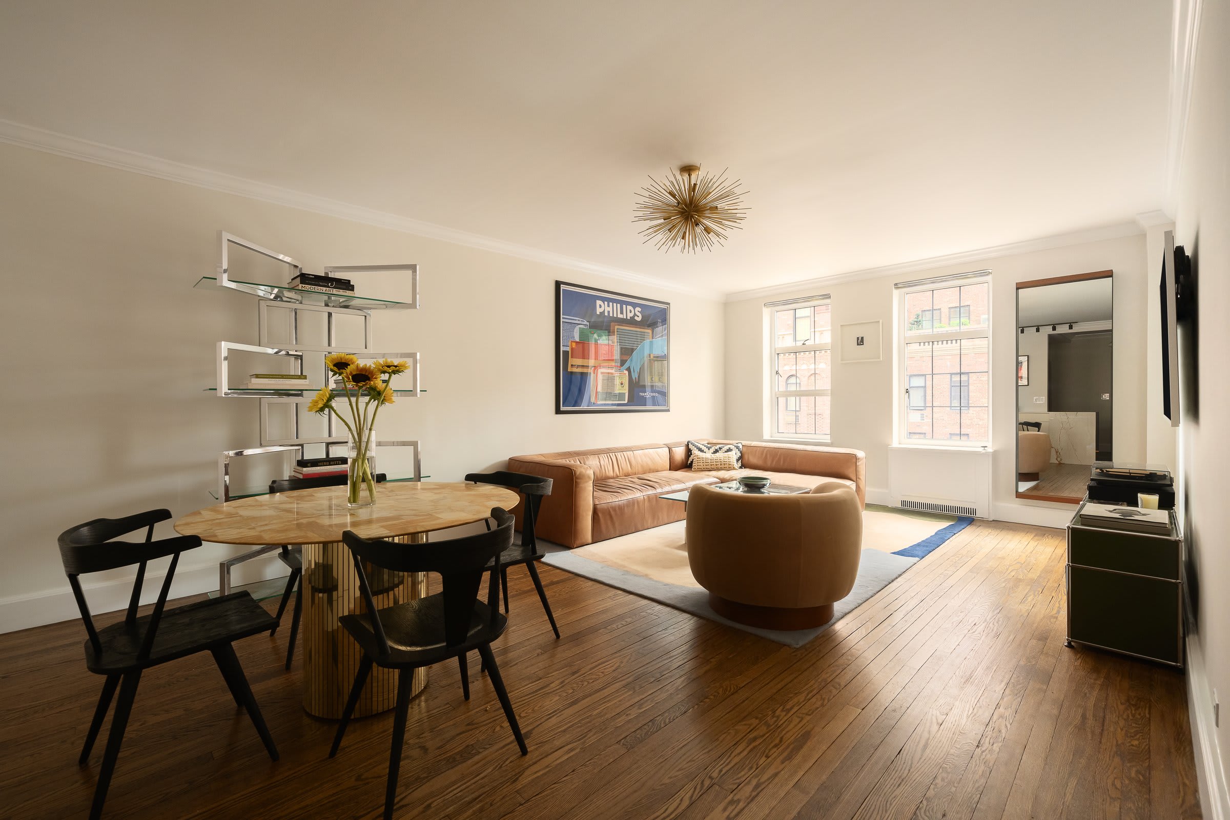The full sweep of the main room of Residence 16J: dining area, living area, and open kitchen in southern light