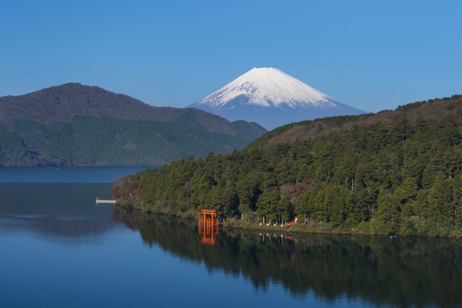 Le torii rouge du sanctuaire de Hakone planté dans le lac Ashi, le mont Fuji enneigé derrière