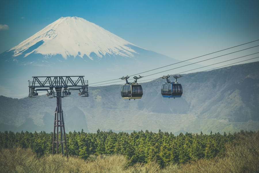 Deux cabines du téléphérique de Hakone au-dessus de la forêt, le mont Fuji enneigé derrière