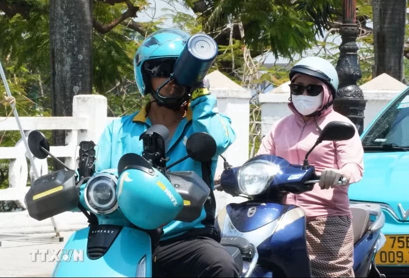 Một lái xe công nghệ ở Huế uống thêm nước khi di chuyển trên đường, để cơ thể tránh mất nước giữa nắng nóng gay gắt. (Ảnh: Nguyên Lý/TTXVN)