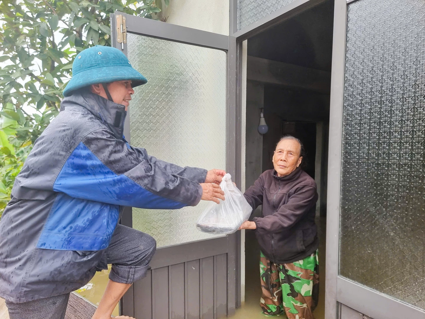 Khoảnh khắc xúc động: Người dân thôn An Thơ, xã Nam Hải Lăng nhận những suất cơm cứu trợ tận tay giữa dòng lũ cô lập - Ảnh: L.T