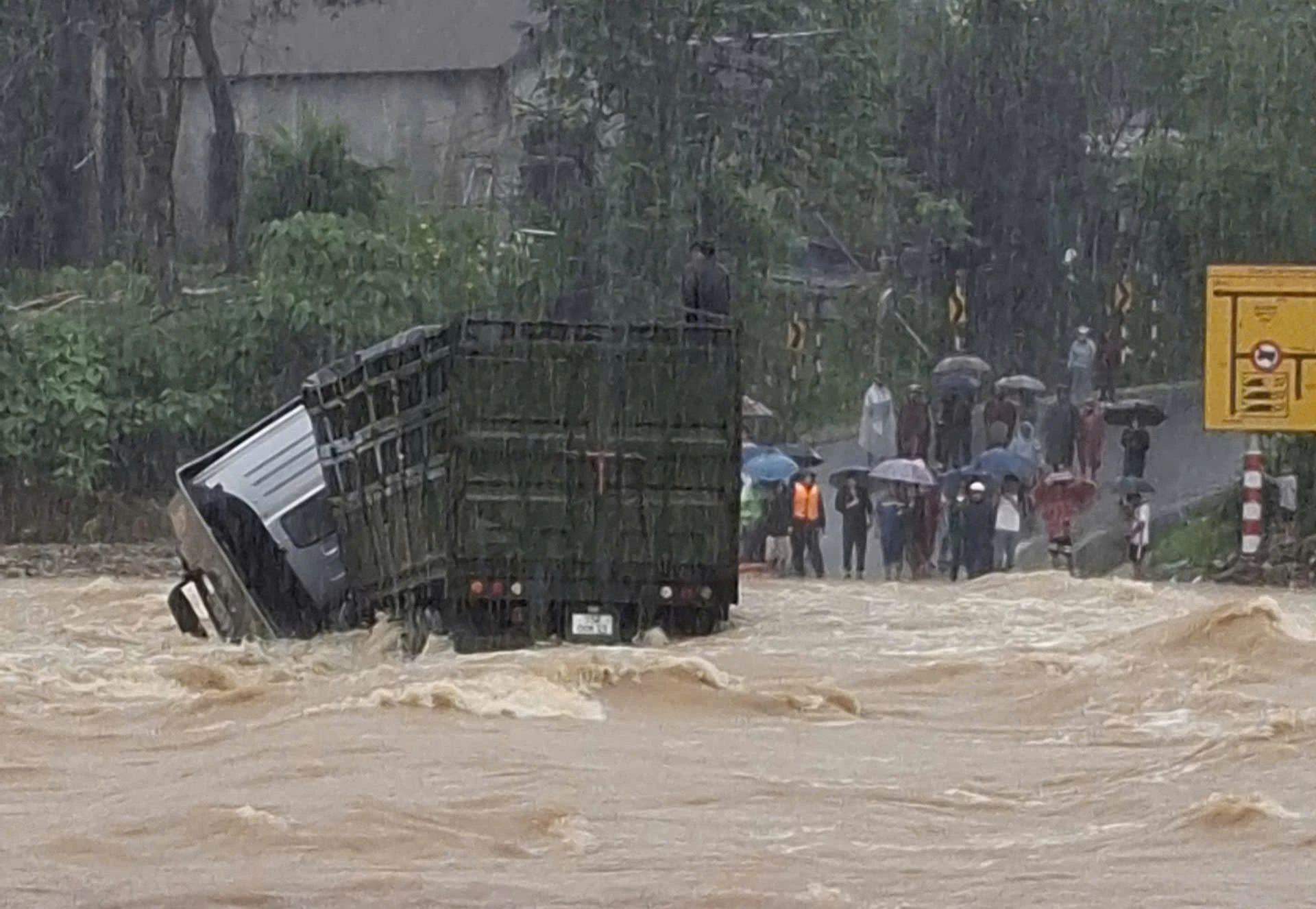 Trước khi bị cuốn trôi, xe container ra giữa ngầm tràn thì bị ngiêng, tài xế cố thoát ra nhưng không kịp - Ảnh: L.T