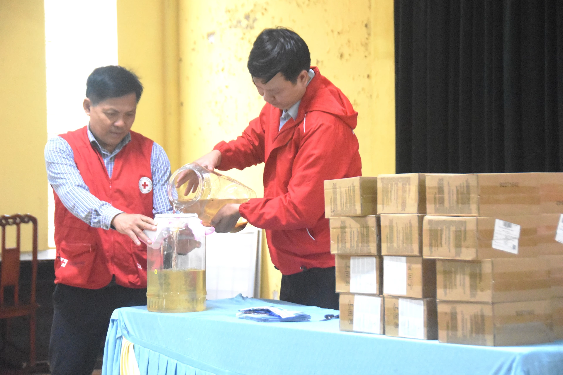 Cán bộ Hội Chữ thập đỏ tỉnh hướng dẫn người dân sử dụng gói bột lọc nước để cải thiện chất lượng nguồn nước trong mưa lũ - Ảnh: ĐV