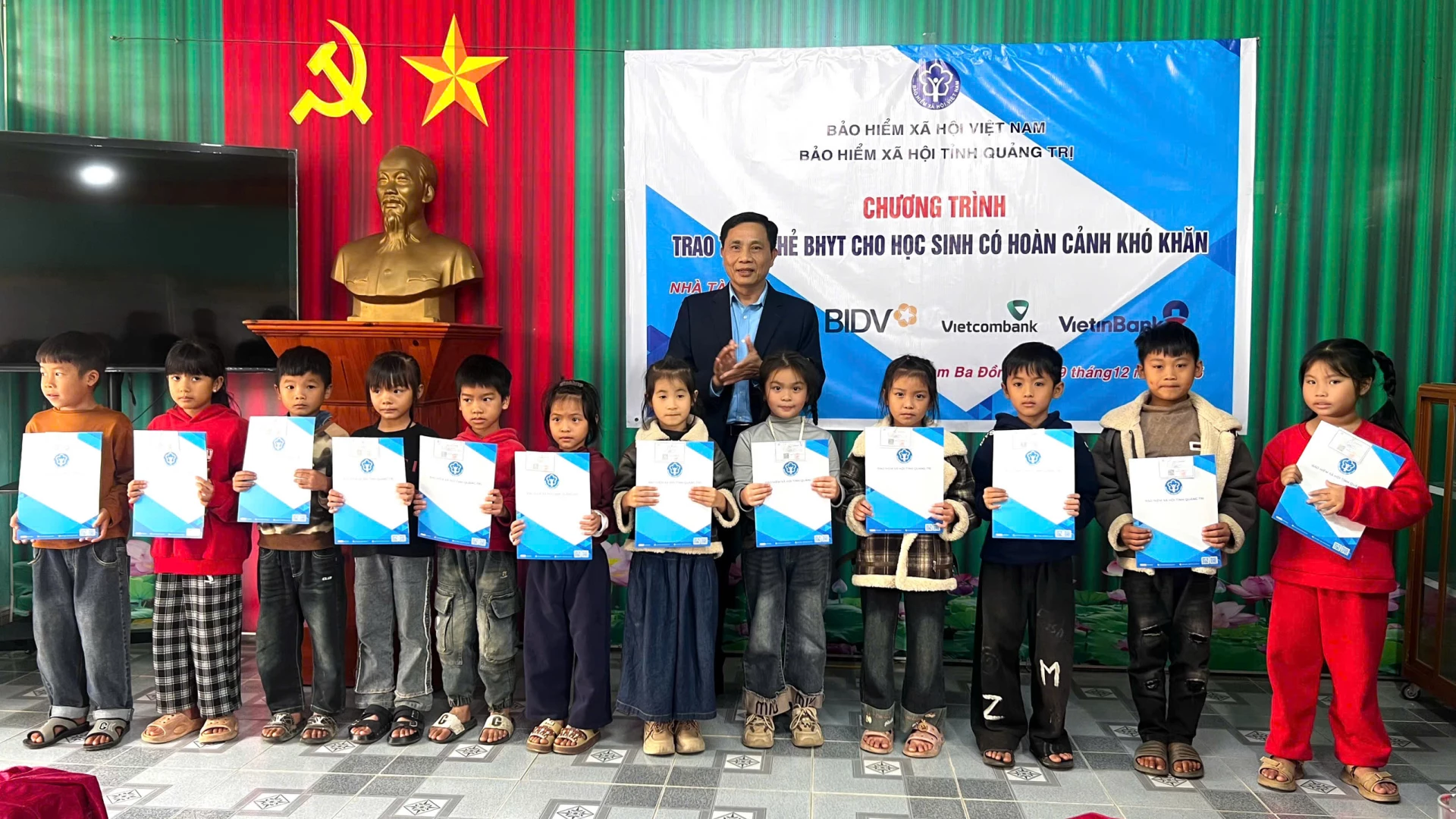 Đại diện Bảo hiểm xã hội (BHXH) tỉnh Quảng Trị trao thẻ BHYT cho các em học sinh có hoàn cảnh khó khăn - Ảnh: H.T