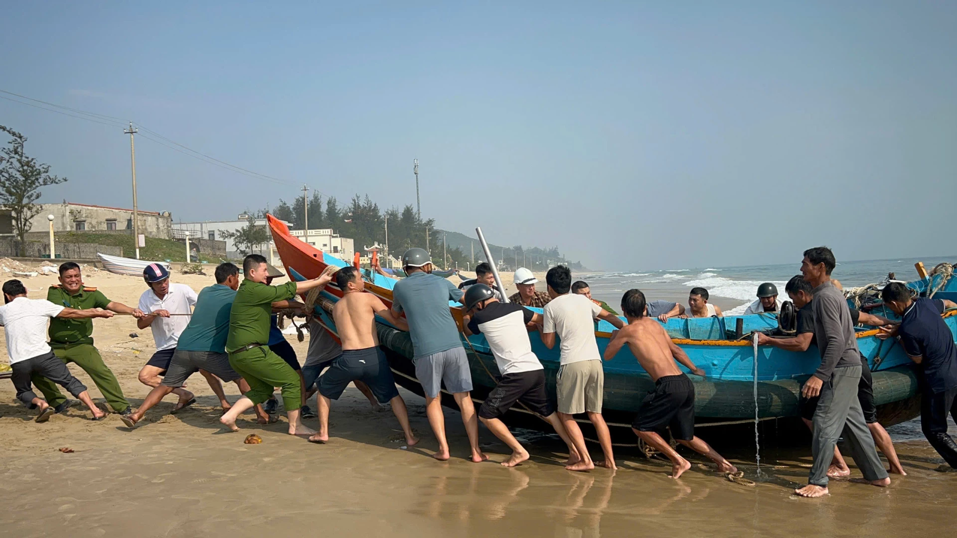 Rất đông người dân và lực lượng chức năng xã Đông Trạch tham gia hỗ trợ cứu kéo thuyền đánh cá gặp nạn - Ảnh: T.L