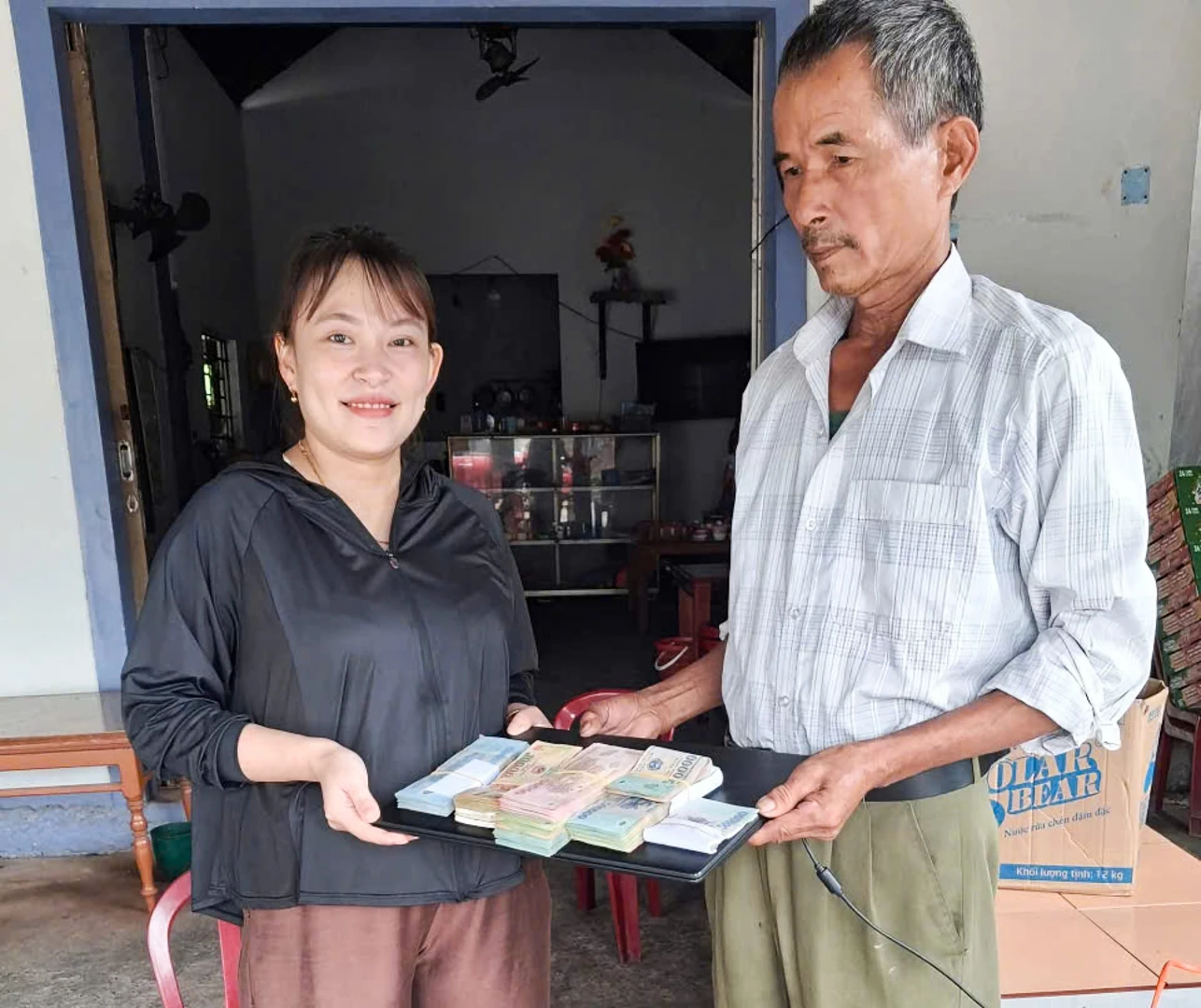 Ông Lưu Văn Biên trao trả tài sản đánh rơi gồm tiền mặt và máy tính xách tay - Ảnh: T.N