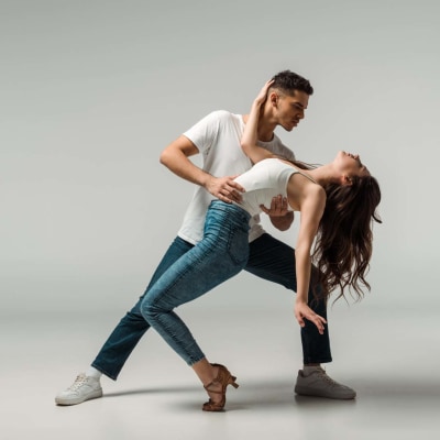 Zwei Tanzende in Jeans im Paartanz vor grauem Hintergrund