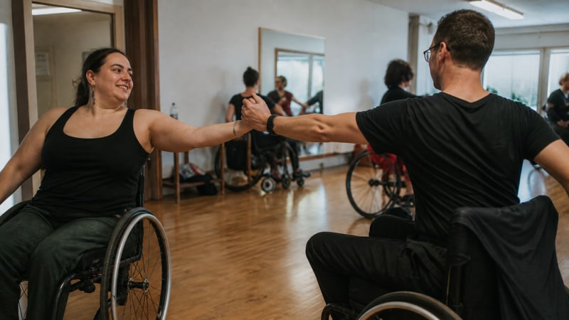Gemeinsame Drehung auf Augenhoehe: Beim inklusiven Paartanz bestimmt die Dynamik zwischen den Partnern den Rhythmus, unabhaengig von Rollstuhl oder Schritten.
