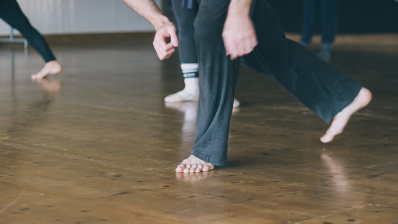 Unterkörper eines männlichen Balletttänzers beim Üben auf einem Hartholzboden in einem Studio