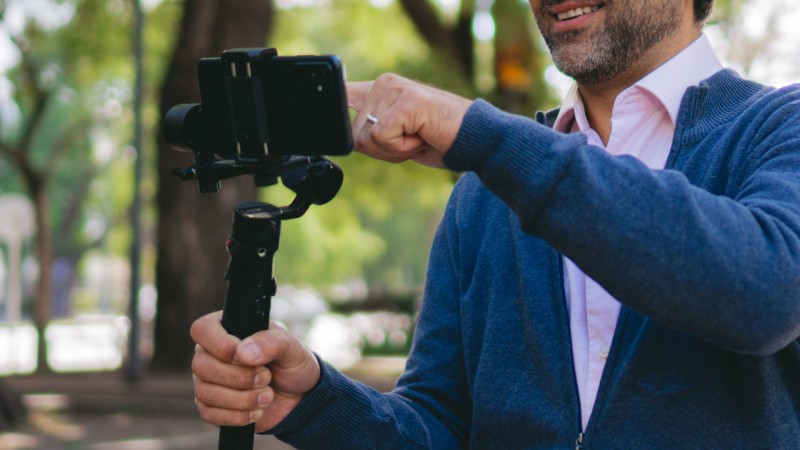 En midaldrende latinamerikansk mand holder sin mobiltelefon i en gimbal og betjener den