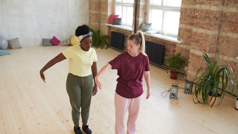 Zwei junge Frauen lernen Bewegungen und Tanz während eines Sporttrainings in einem Tanzstudio