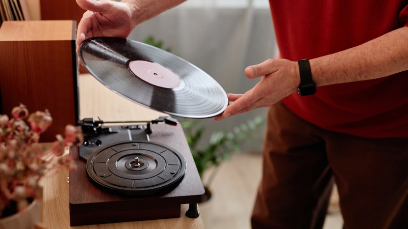 Ein älterer Mann legt eine Schallplatte auf einen Retro-Plattenspieler