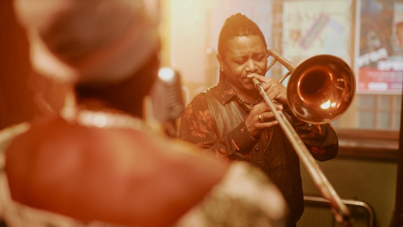 Ein Mann spielt Posaune auf einer Bühne mit einer Jazzband