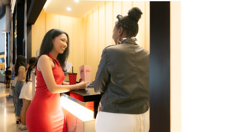 Nữ nhân viên bán vé người châu Á tại quầy vé đang bán vé cho khách xem phim
