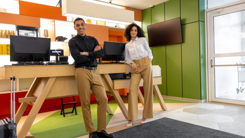 To glade og selvsikre hotelreceptionister bag en reception