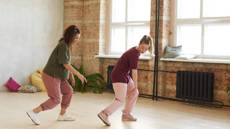 Zwei junge Frauen tanzen zusammen und lernen einen neuen Tanz in einem Tanzstudio