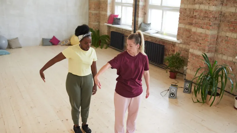 Zwei junge Frauen lernen während eines Sporttrainings in einem Tanzstudio Tanzbewegungen