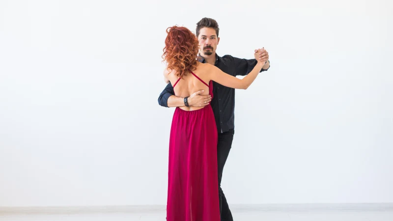 Ein Paar tanzt Salsa, Kizomba oder Tango vor einer weißen Wand mit freier Fläche