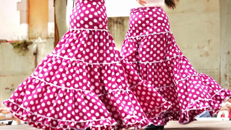Ein Paar Flamencotänzer führt Sevillanas in pinkfarbenen Röcken mit Punkten, Rüschen und Volants auf