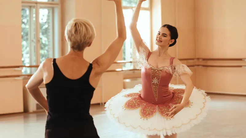 Lächelnde Balletttänzerin und ihre Tanzlehrerin beim Tanzen im Ballettstudio
