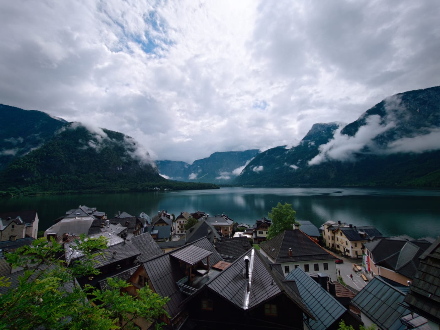 Hallstatt rooftops and lake surrounded by steep mountains with clouds over the water