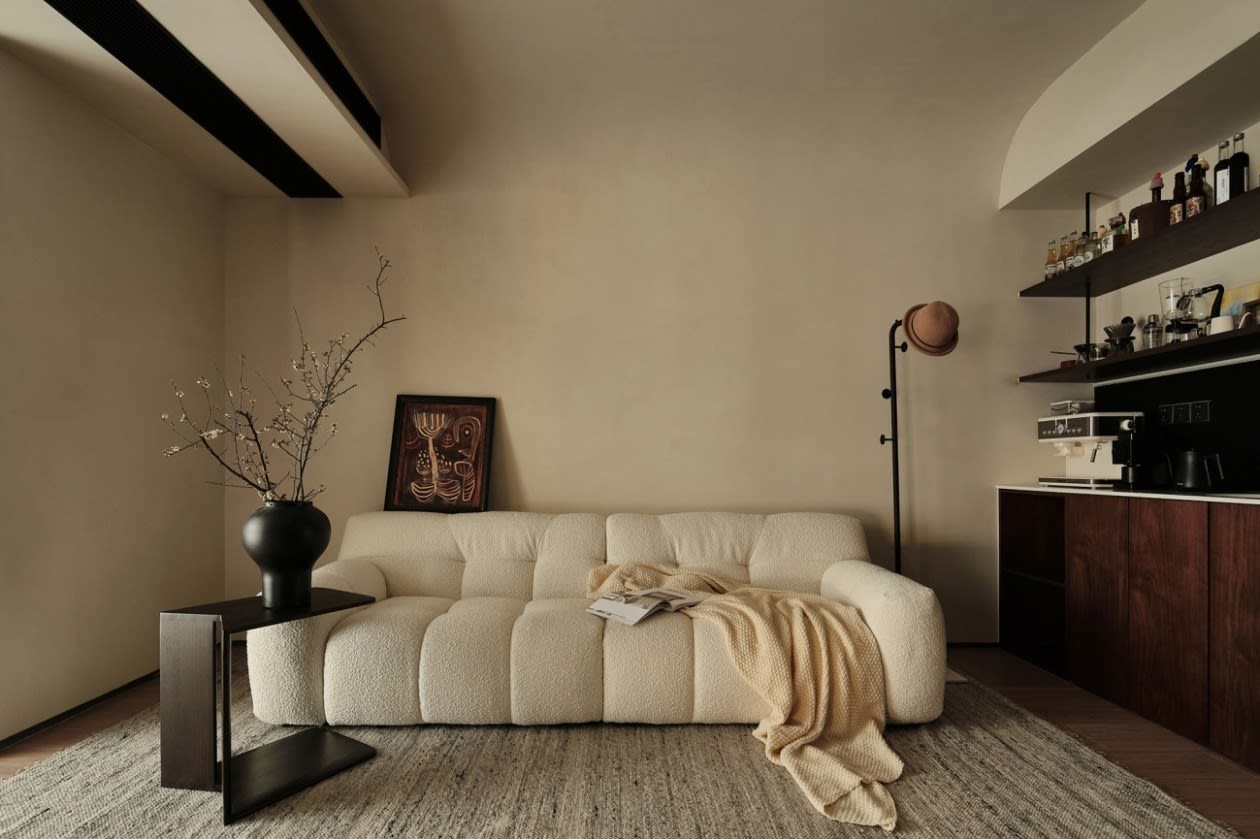 Warm minimalist living room with neutral earth tones, natural wood furniture, and soft linen textiles