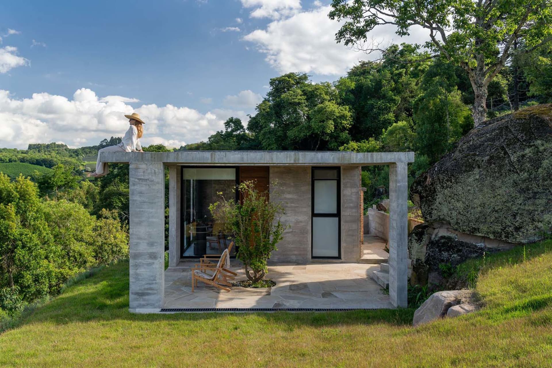 A modern exterior concrete retreat shelter surrounded by trees.