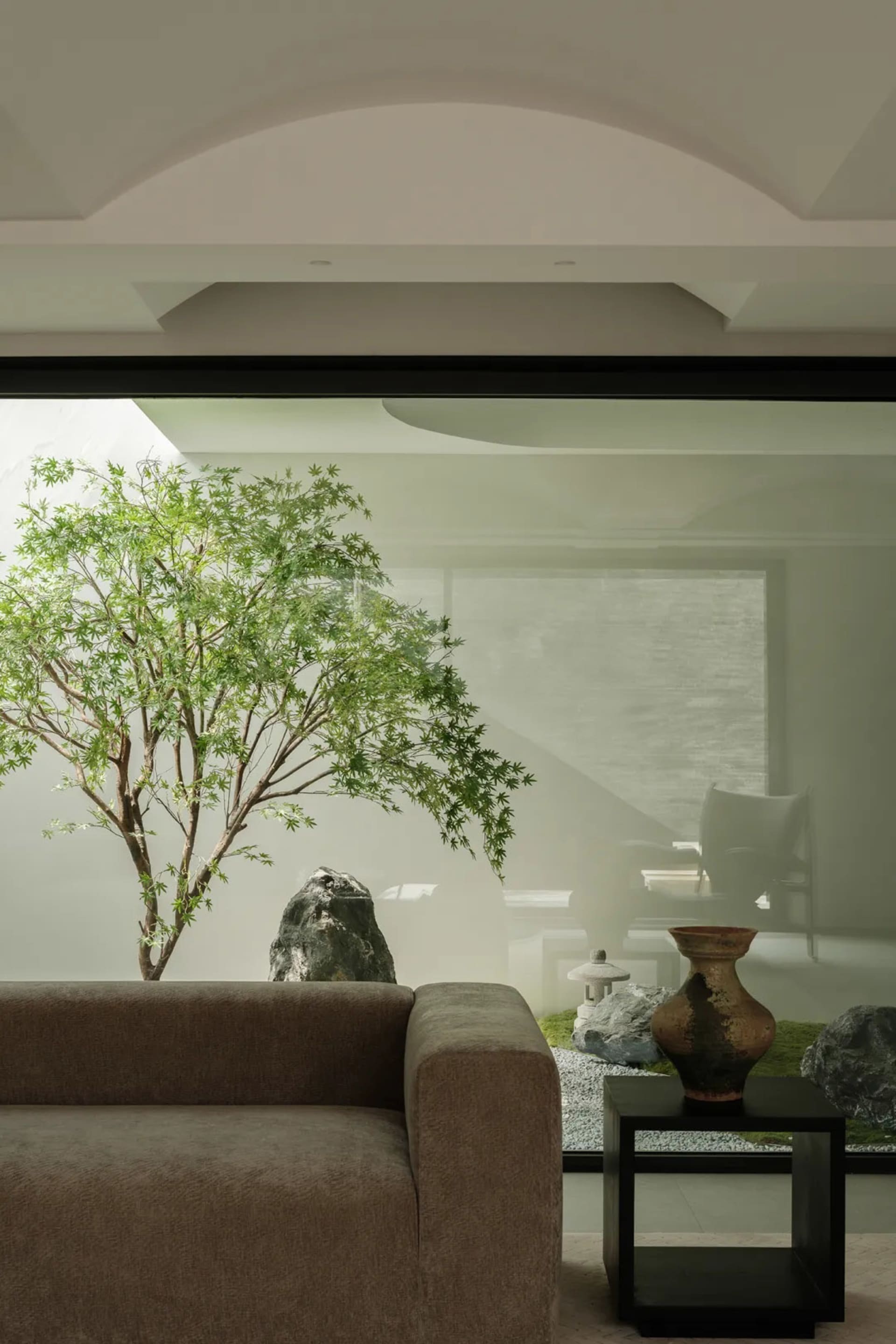 Modern living room with a zen garden featuring concrete, rock, and glass elements