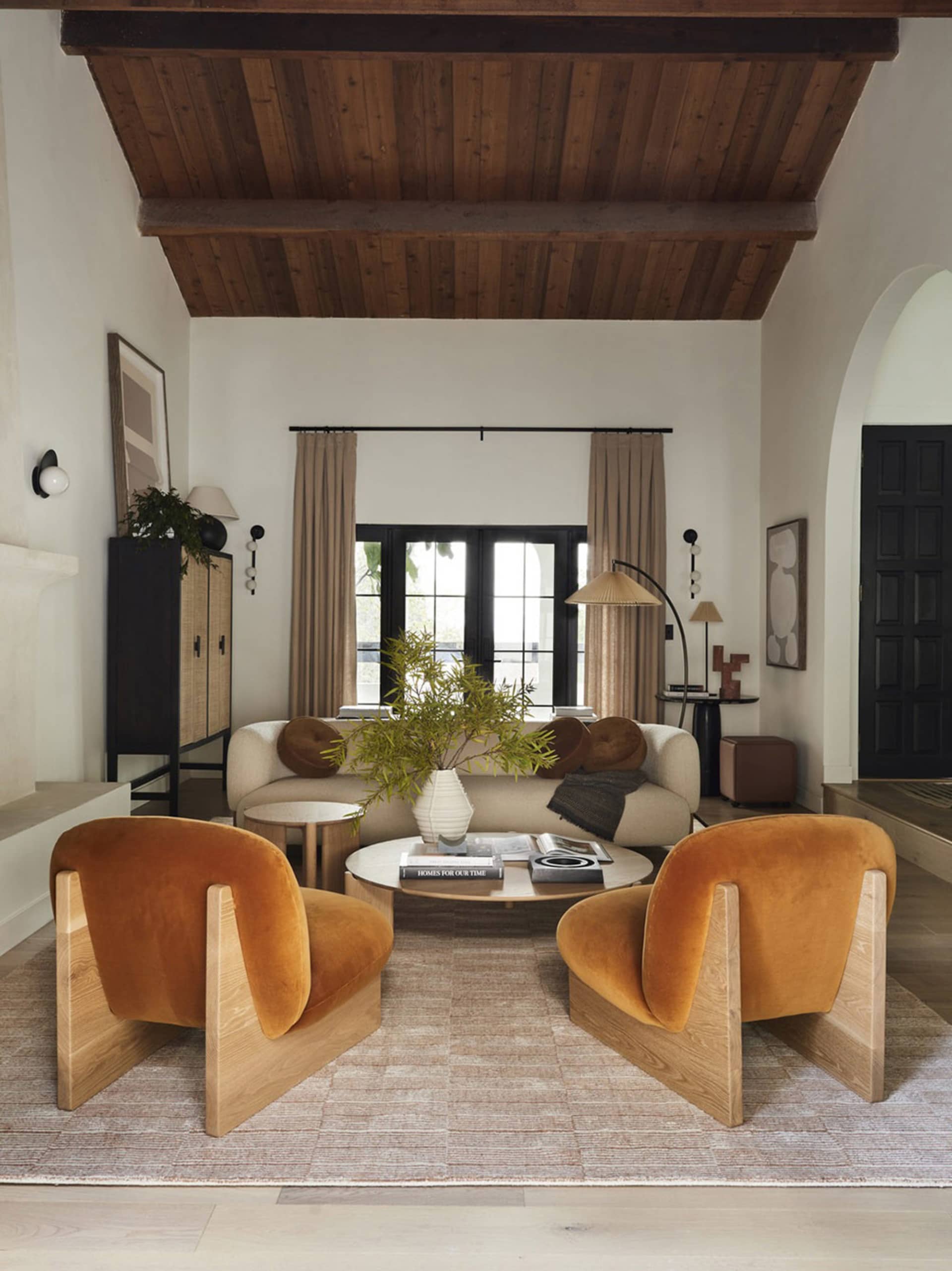 Modern living room featuring velvet chairs and wooden accents.